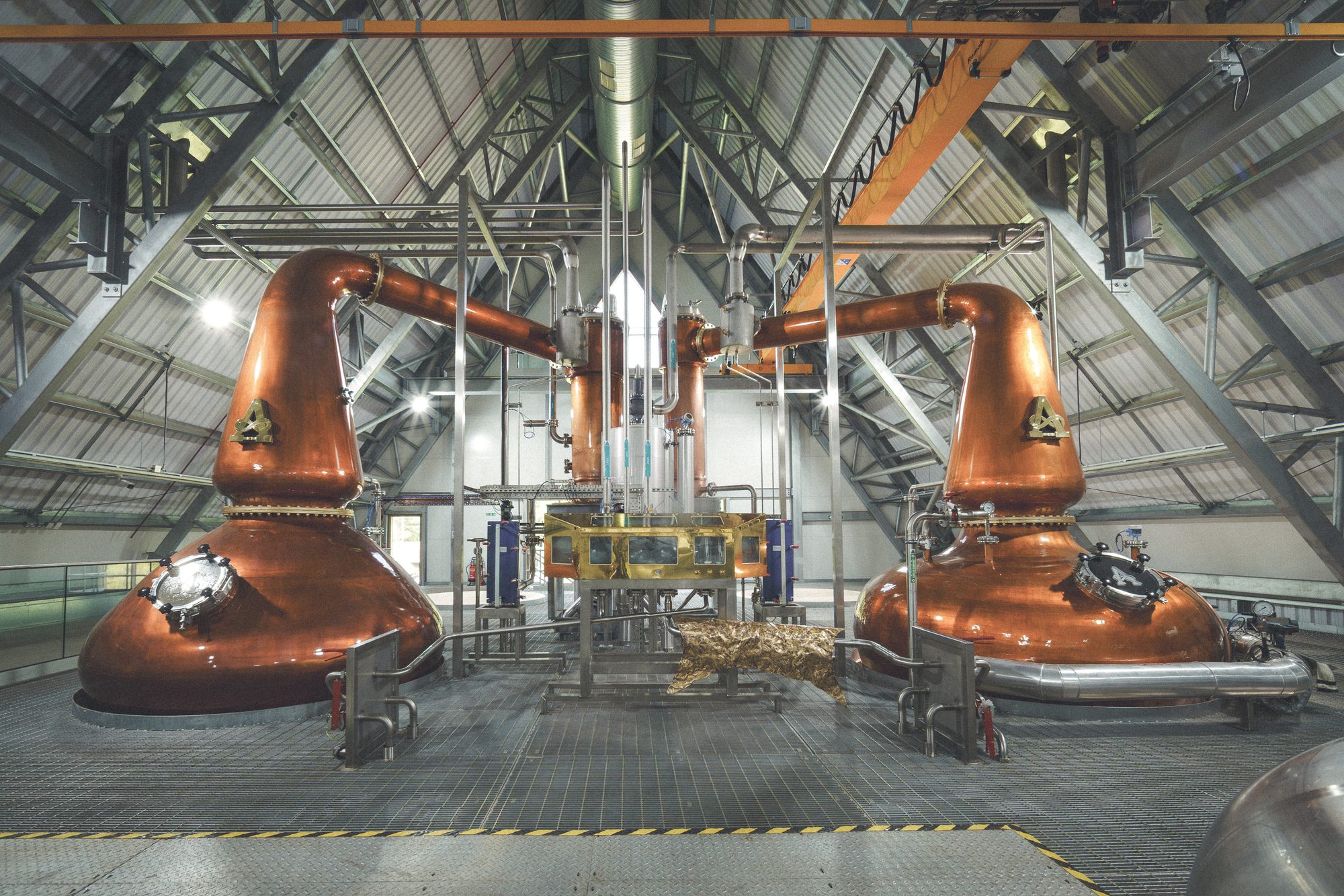 Ardgowan Distillery, Inverkip — die beiden kupfernen Brennblasen unter dem Dreiecksgerüst des Dachtragwerks, darüber die Kranbahn