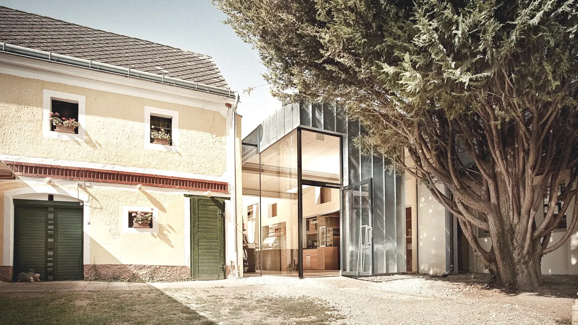 Gössinger, Weinviertel — gläserner Zubau zwischen Altbau und Baum bei Tag