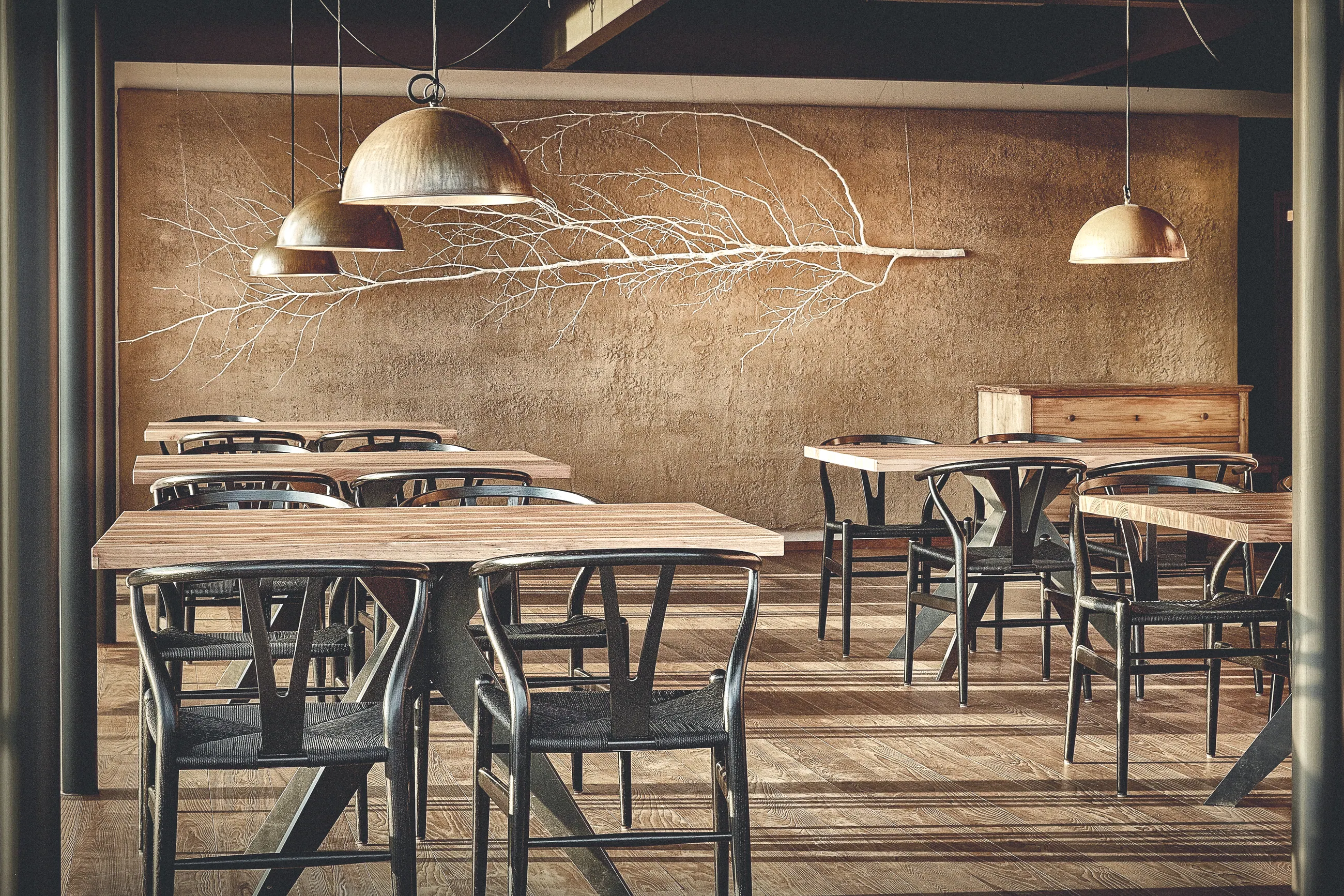 Restaurant Lurgbauer, Steiermark — Gastraum mit Astinstallation an der Wand und Messingleuchten