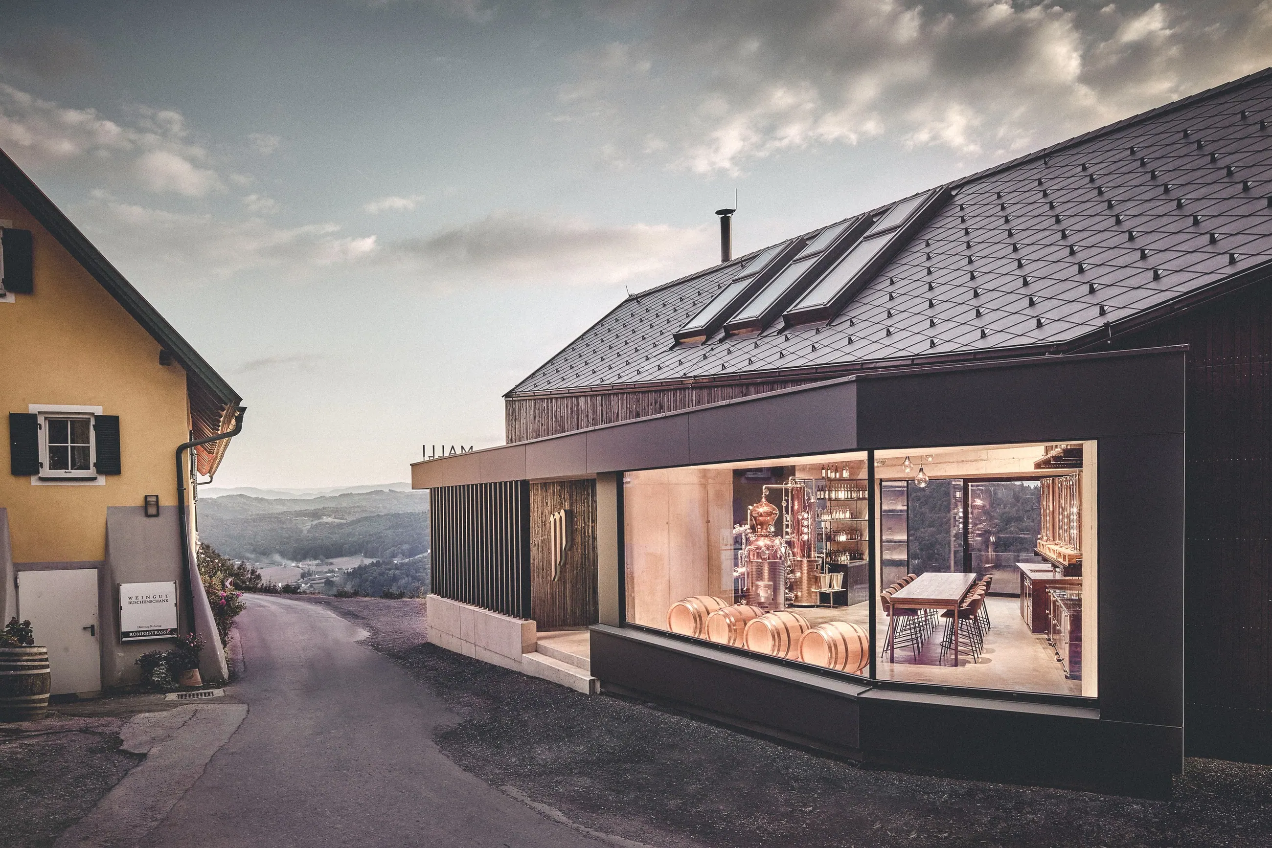 Weingut Malli, Südsteiermark — beleuchteter Verkostungsraum hinter der Panoramascheibe an der Strasse