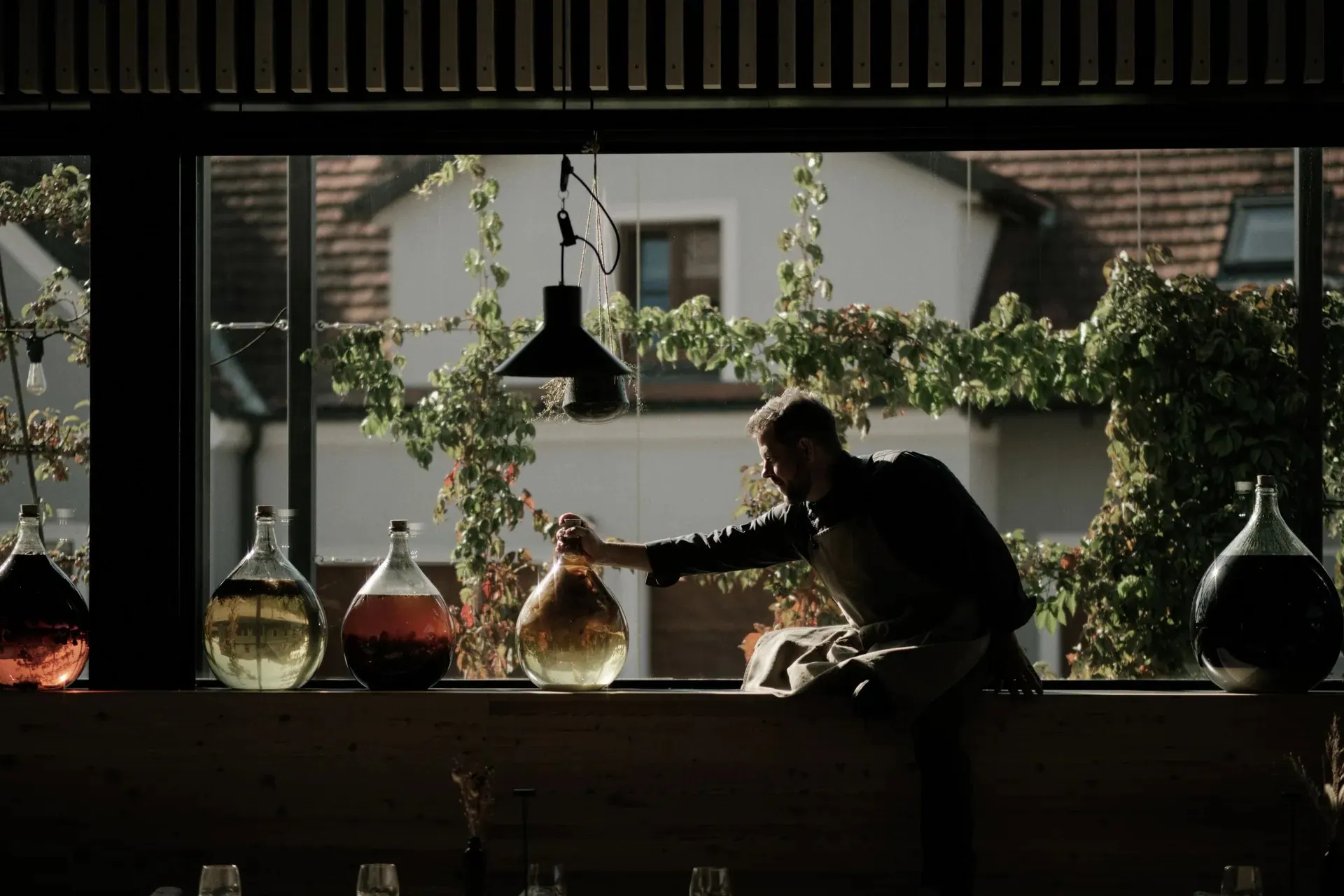Gasthaus Nährer, Weinviertel — Mitarbeiter an der Schank mit Glasballons vor der Fensterfront