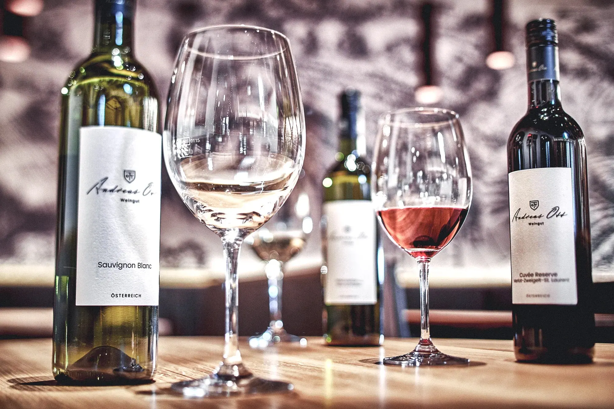 Andreas Ott, Weinviertel — Flaschen und Gläser mit Weiss- und Rotwein auf dem Tisch