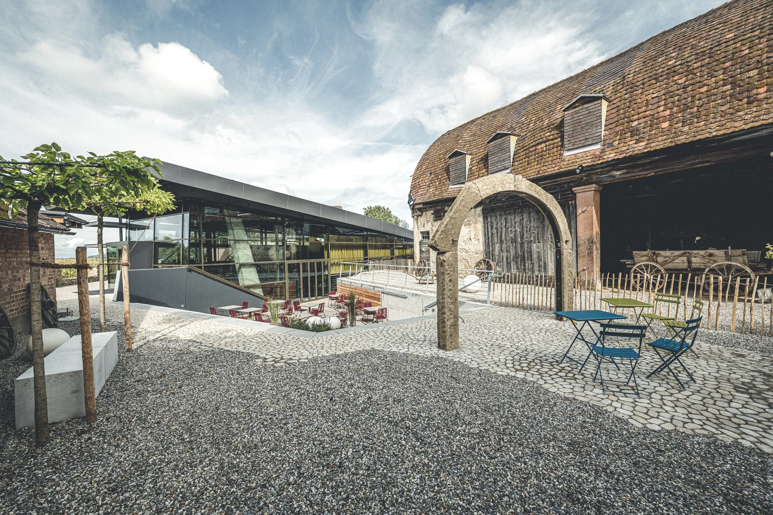 Schüler · Genussspielhaus, Baden — Glasanbau neben der historischen Scheune mit Rundbogentor