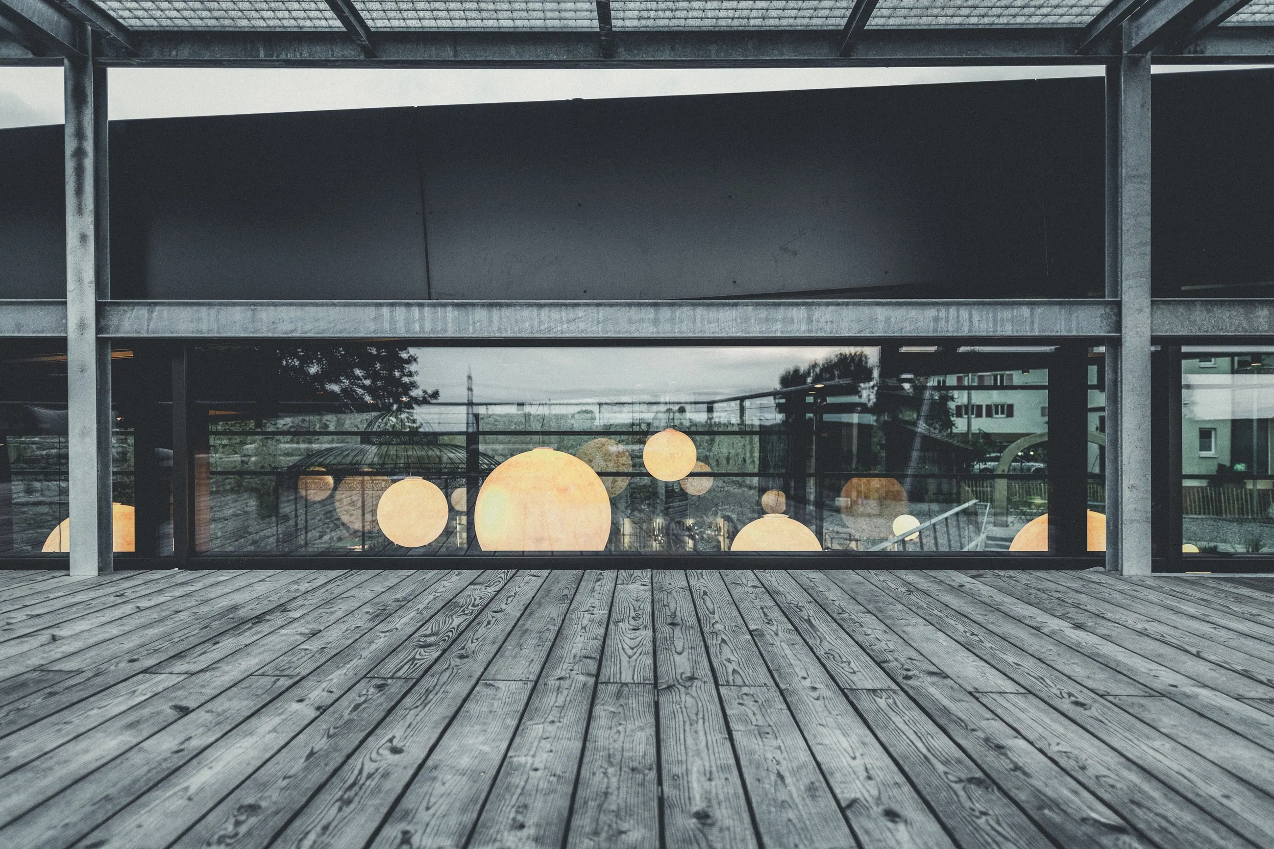 Schüler · Genussspielhaus, Baden — Holzterrasse vor der Glasfront mit Lichtkugeln