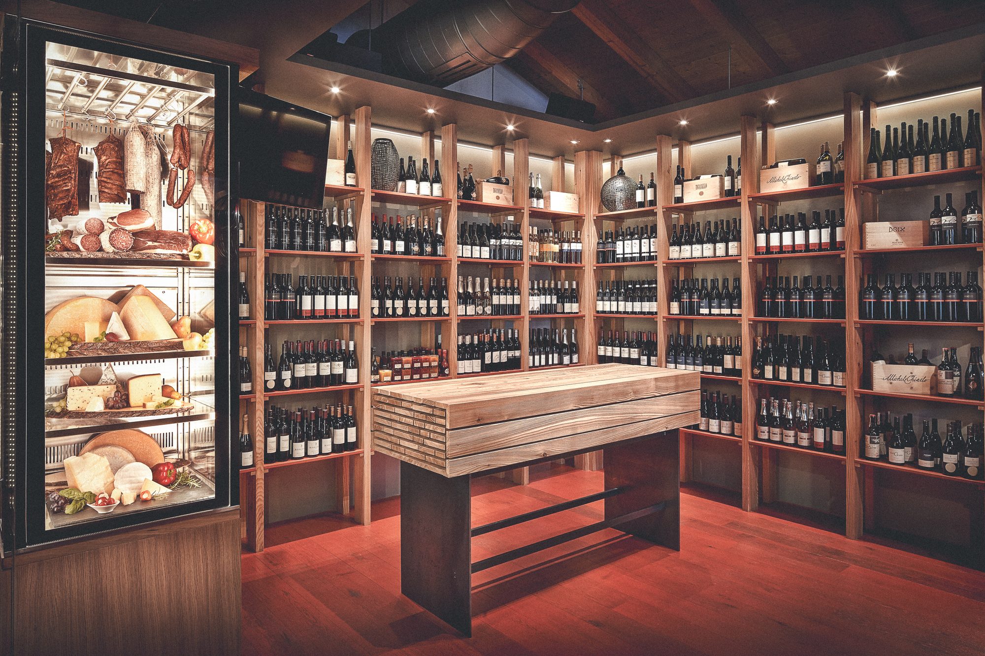 Restaurant Steiner, Pinsdorf — Vinothek mit raumhohen Weinregalen und Verkostungstisch aus Massivholz