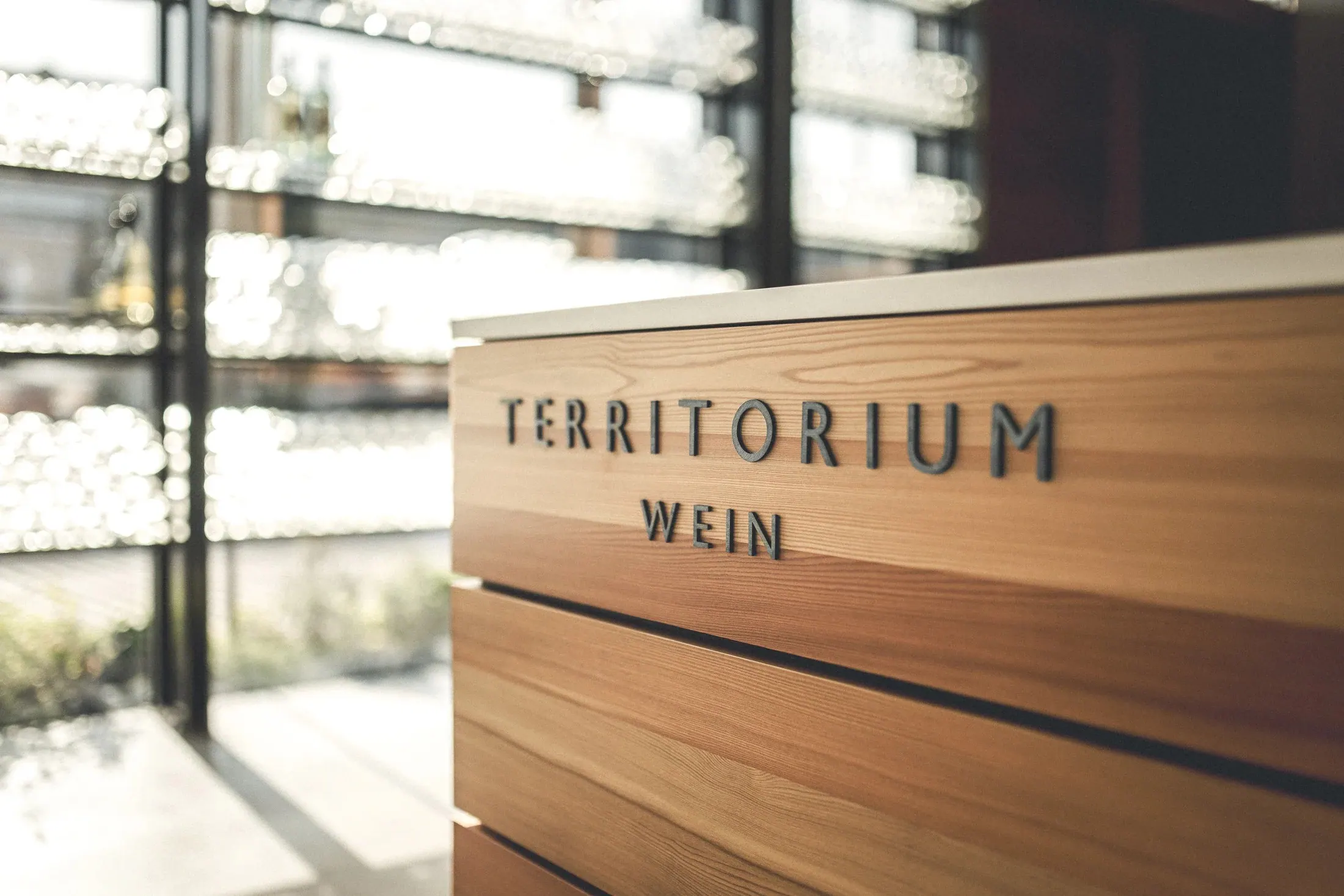 Weinwurm, Weinviertel — Holzpult mit Schriftzug „Territorium Wein“ vor der Flaschenwand