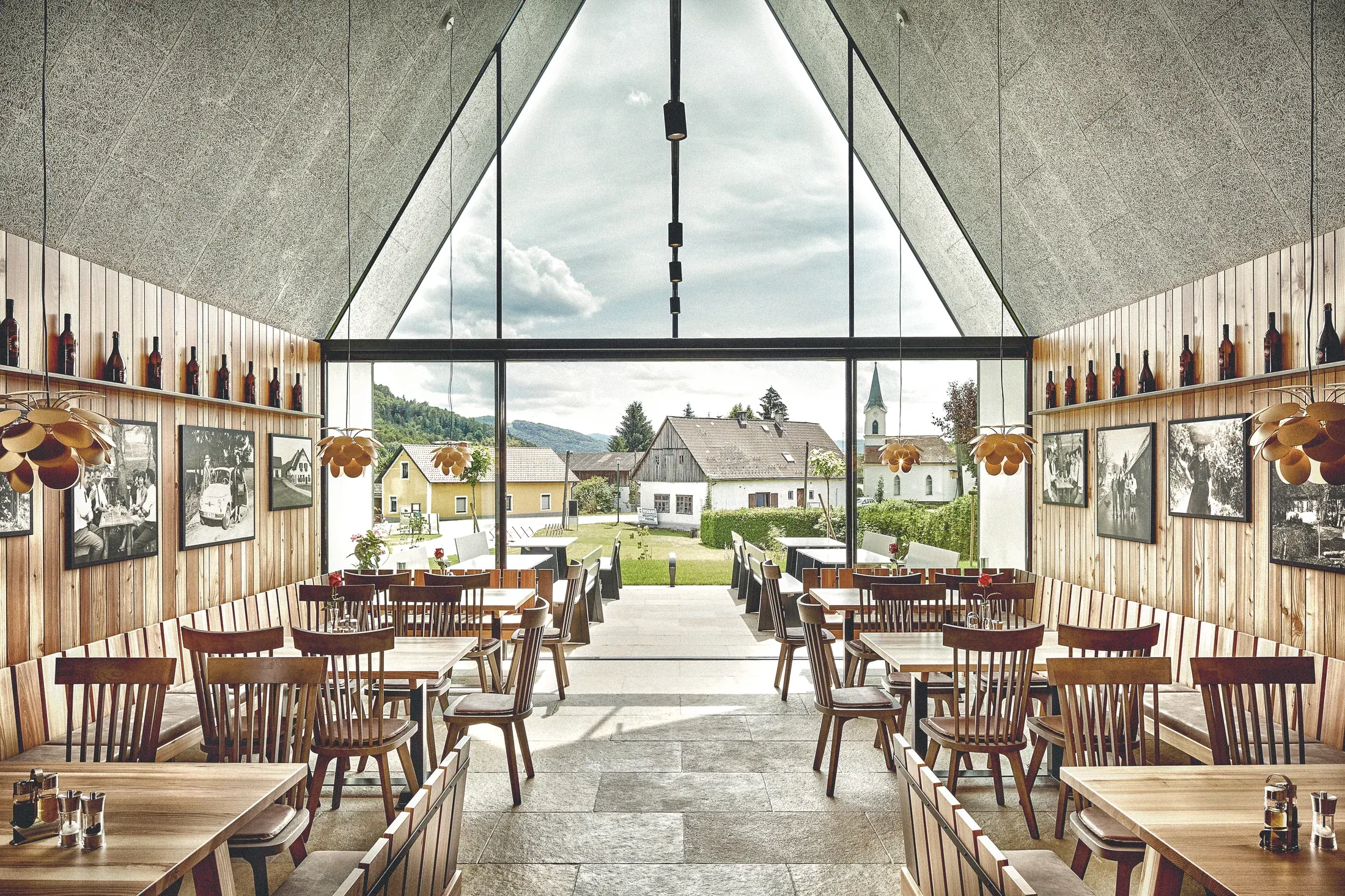 Weingut Wutte, Südsteiermark — Gastraum mit Panoramaverglasung im Giebel und Blick ins Dorf